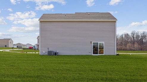 rear exterior view of the home featuring a large well landscaped backyard
