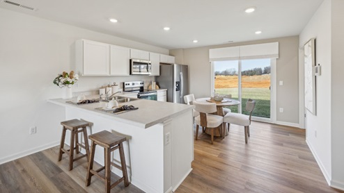 modern kitchen with white cabinetry, stainless steel appliances, 2 counter stools, and a large sliding door to the backyard