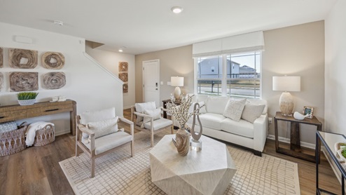 open concept living room with tan and white decor overlooking a TV on the back wall
