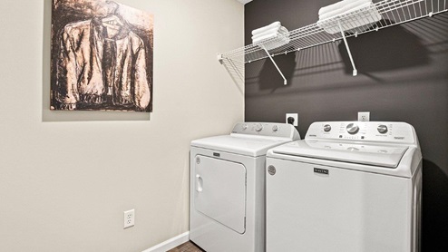 Parlor Bluffs Henley Model Laundry Room with Washer and Dryer, LVP Flooring, and Wire Shelving.