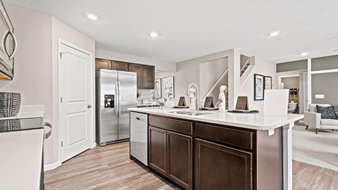 Parlor Bluffs Henley Model Kitchen with large island with stainless steel sink and dishwasher with space for storage with extra cabinetry.