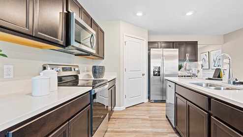 Parlor Bluffs Henley Model Kitchen with dark sarsparilla cabinetry and Miami White Quartz Countertops