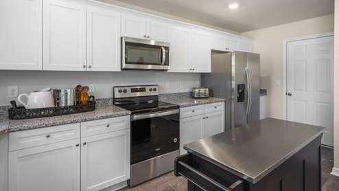 kitchen island with stainless steel top adjacent to whirlpool stainless steel appliances.