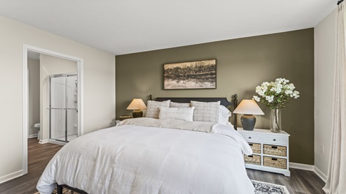 Bedroom with a green accent wall with brown flooring.