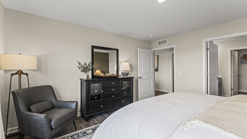 Bedroom with brown flooring and an ensuite bathroom.