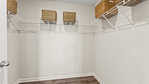 Large walk in closet with brown flooring.