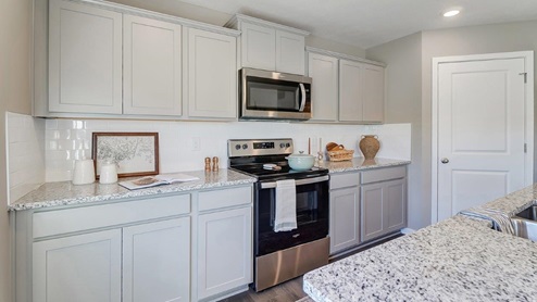 kitchen with grey cabinets, stainless steel appliances and corner walk in pantry