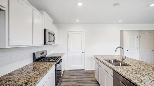 white cabinets, hard surface counters, stainless steel appliances, walk in pantry, built in island