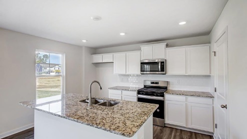 kitchen with single window, white cabinets, stainless appliances, walk in pantry, built in island