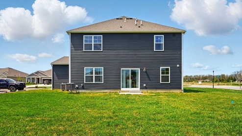 rear exterior of home featuring a concrete patio and spacious backyard