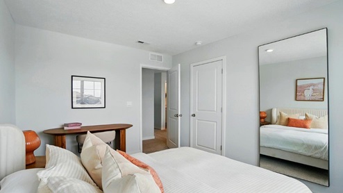 bedroom featuring a queen bed with white bedding and pops of orange decor and a large window