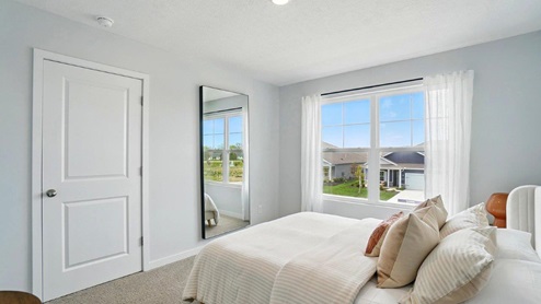 bedroom featuring a queen bed with white bedding and pops of orange decor and a large window