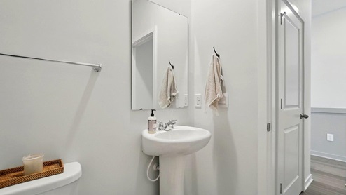 powder bathroom featuring a toilet, pedestal sink and mirror above