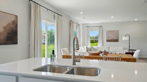 spacious modern kitchen featuring white cabinetry, large island and stainless steel appliances