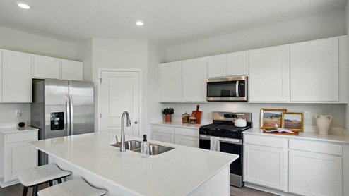 spacious modern kitchen featuring white cabinetry, large island and stainless steel appliances