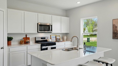 spacious modern kitchen featuring white cabinetry, large island and stainless steel appliances