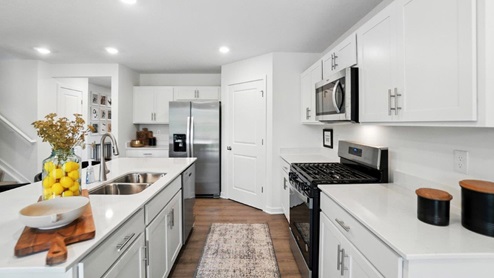 kitchen with built in island with barstools, white cabinets, stainless steel appliances and corner walk in pantry