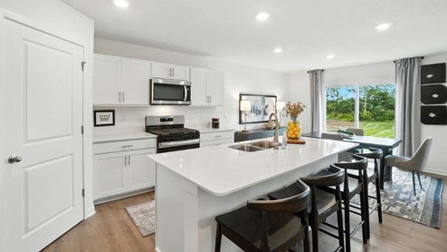 kitchen with built in island with barstools, white cabinets, stainless steel appliances and corner walk in pantry