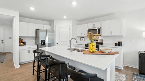 kitchen with built in island with barstools, white cabinets, stainless steel appliances and corner walk in pantry