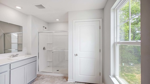 Interior primary bathroom with double sink and shower and large window