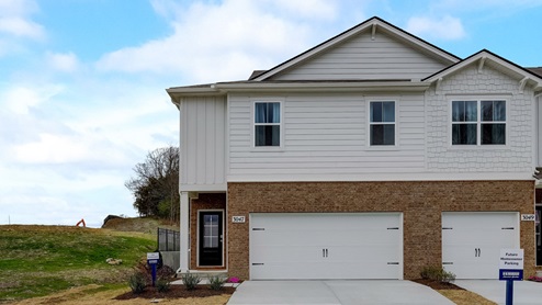 Front of two story townhome with brick and white exterior during the day