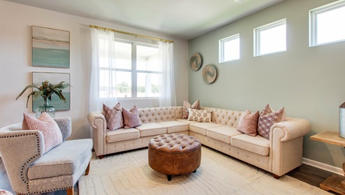 bristol plan living room riverwood gardens community with large double-window overlooking the backyard and 3 picture windows along opposing wall offering natural light and privacy