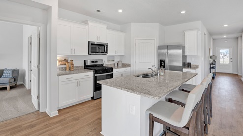 Kitchen area opens up at the end of long entryway