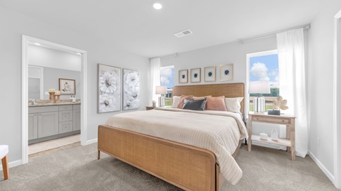 Beautiful primary bedroom with two tall windows overlooking the side yard