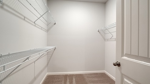 Spacious primary closet with ventilated shelving for additional storage