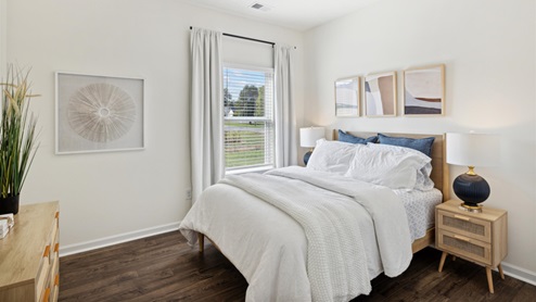 Secondary bedroom with wood-look flooring, a double bed flanked by two nightstands, and a dresser.