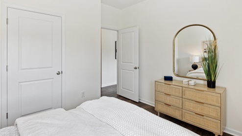 Looking across the secondary bedroom's bed towards the dresser and doorway into the hall.