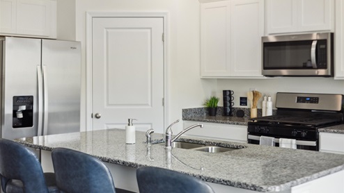 Kitchen with white, shaker-style cabinetry, granite countertops, and stainless-steel appliances.