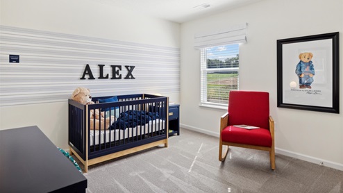 Secondary bedroom decorated in a teddy-bear theme with a crib, nightstand, rocking chair, and changing table.