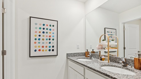 Secondary bathroom with a double vanity and a simple, colorful art print on the wall.