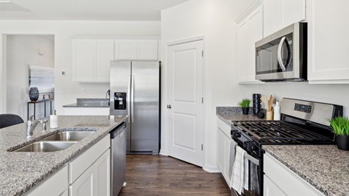 Kitchen with white, shaker-style cabinetry, granite countertops, and stainless-steel appliances.
