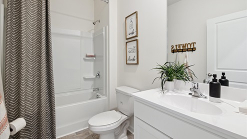 Hall bathroom with white cabinets and single sink