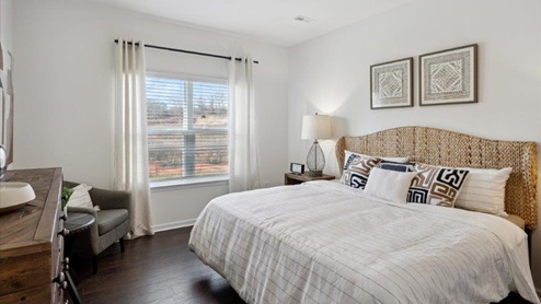 primary bedroom with king size bed, dresser, and chair