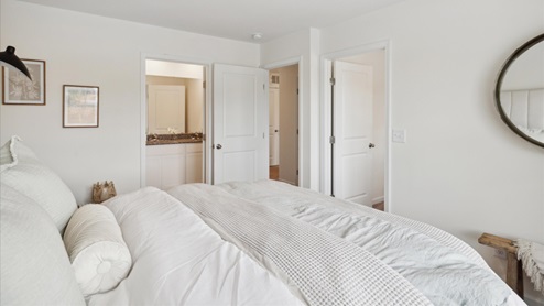 Primary Bedroom with carpet and white walls leading into primary bathroom