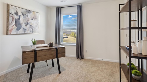 Office area brown wooden desk with tan chair on the left hand side next to a window and a bookshelf on the right