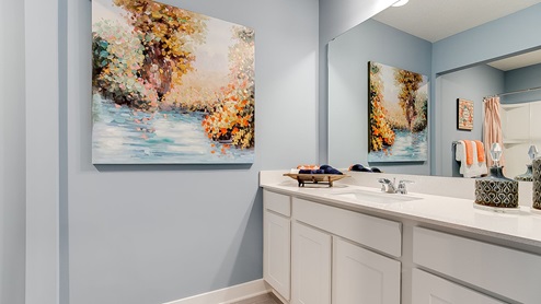 Secondary bathroom with white cabinets and quartz vanity countertop.