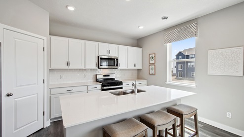 Kitchen with white cabinetry and quartz countertops.