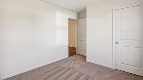 Bedroom with carpet, white walls and closet door.