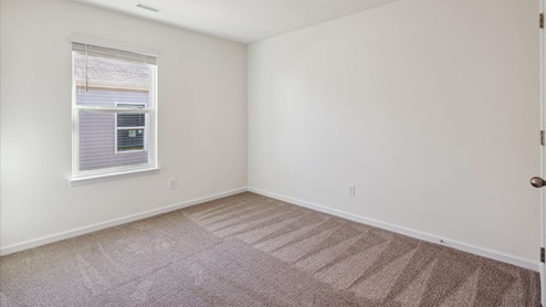 Bedroom with carpet, white walls and window.