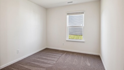 Bedroom with carpet, white walls and window.