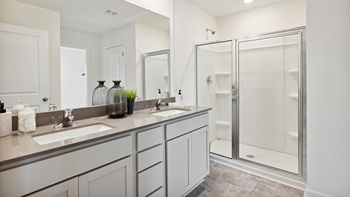 Interior primary bathroom with two sinks and walk in shower