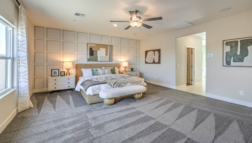 The Bedroom One Suite in our Symmetry Manor 2538 model with carpet flooring, large windows, a walk-in closet, and a ceiling fan with a light kit.