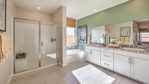 Attached to the Bedroom One Suite, our 2538 model bathroom with granite countertops at the double Bath Vanity, a walk-in shower, bath tub, mirror, and white cabinets.