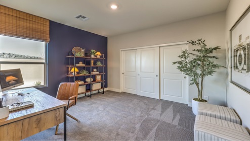 The Office/Bedroom three option in our Symmetry Manor 2754 model with carpet flooring, a sliding closet, and a window, furnished with a desk and chair.