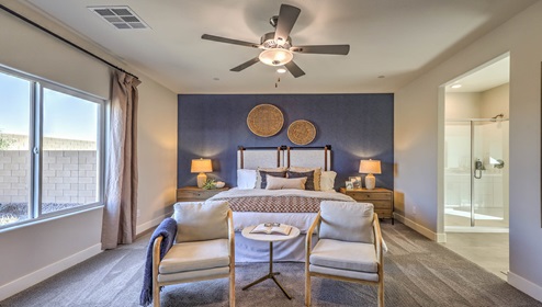 The Bedroom One Suite in our Symmetry Manor 2754 model with carpet flooring, large windows, a walk-in closet, and a ceiling fan with a light kit.