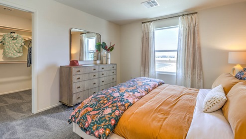 The Bedroom One Suite in our Spectrum Trails 1334 model with carpet flooring, two windows, recessed ceiling lights, and a walk-in closet.